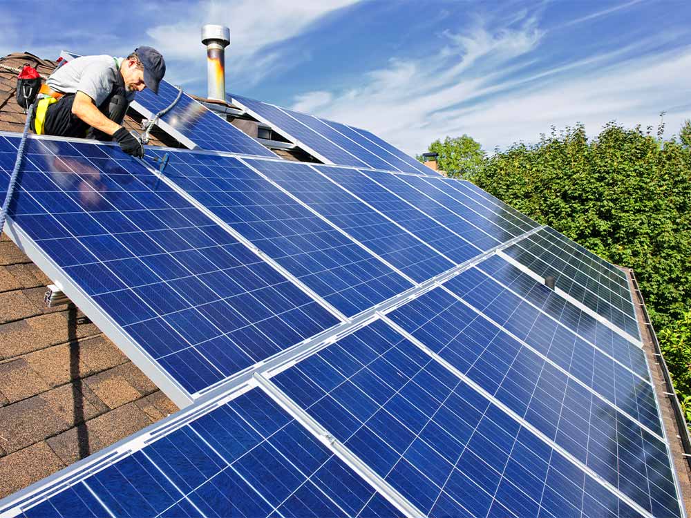 Worker installing solar panels on roof
